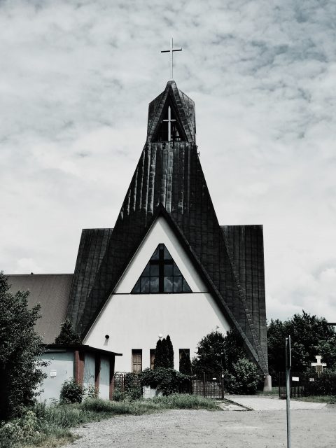 a white church stands against a grey sky.
