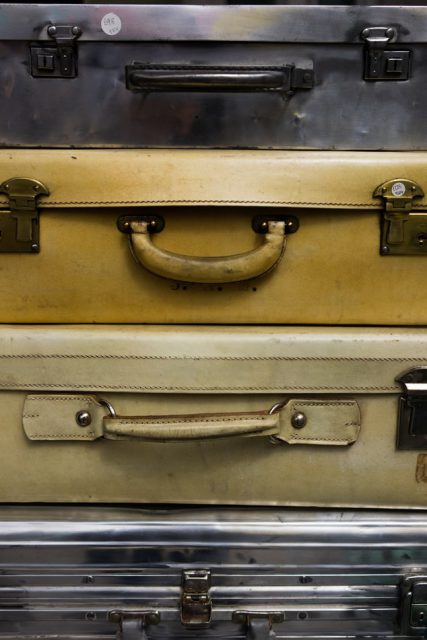Four vintage suitcases are stacked on top of each other and fill the entire frame.
